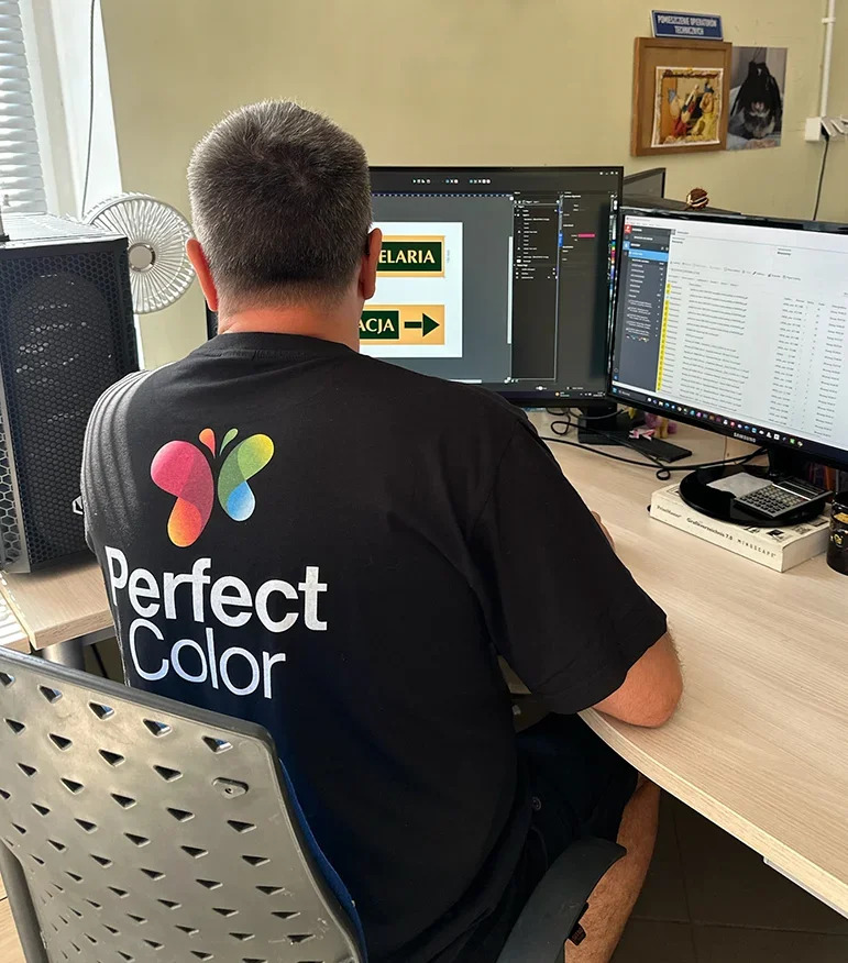 Pracownik przy komputerze przygotowujący projekty do druku i produkcji